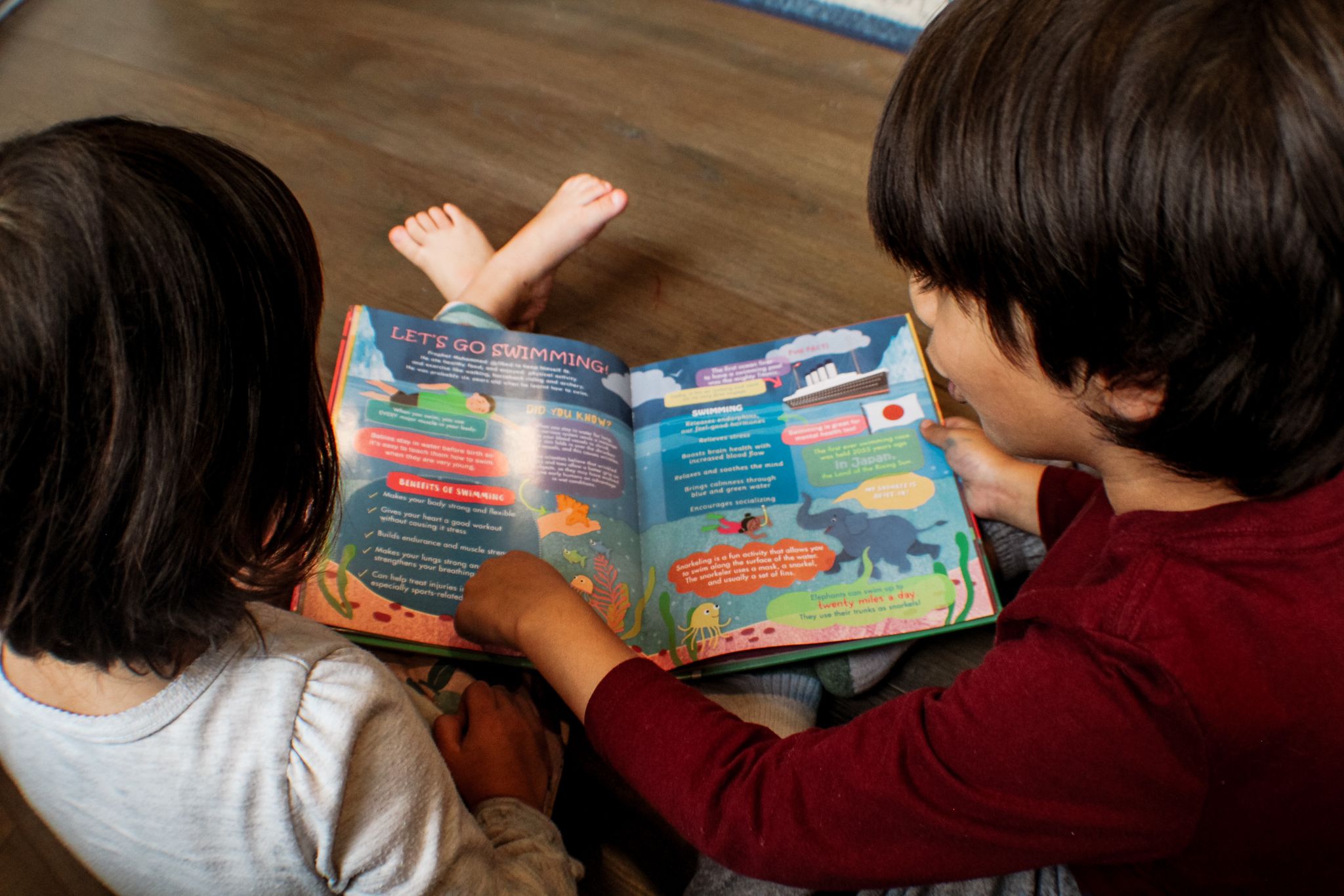 Two children sitting on the floor while reading sunnah and science