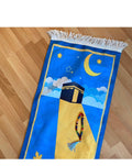 A rectangular blue and yellow children's prayer rug with a design of a mosque and stars, featuring a tassel on one corner.