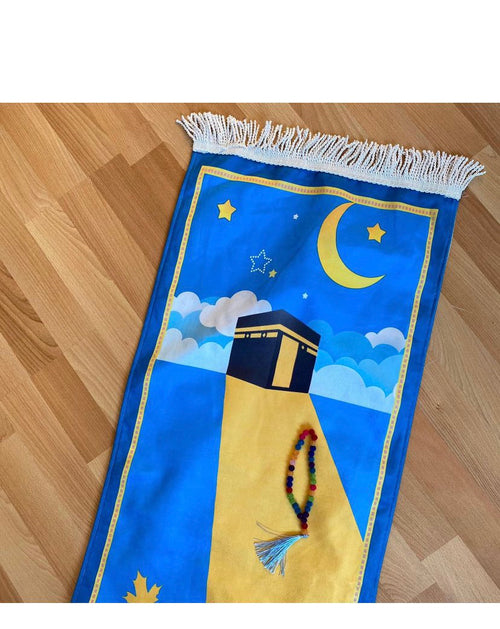 A rectangular blue and yellow children's prayer rug with a design of a mosque and stars, featuring a tassel on one corner.