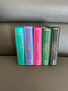 from left to right; a turquoise quran, a purple quran, a hot pink quran, and green quran, black quran