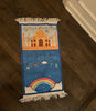 a dark blue bordered prayer rug, with a mosque at the top with a rainbow underneath. 