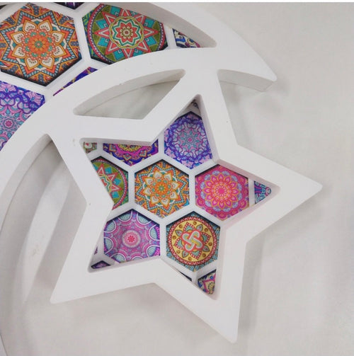 A white serving tray with colorful geometric patterns in various shapes, resembling stars and crescents, predominantly used for Islamic festivities.