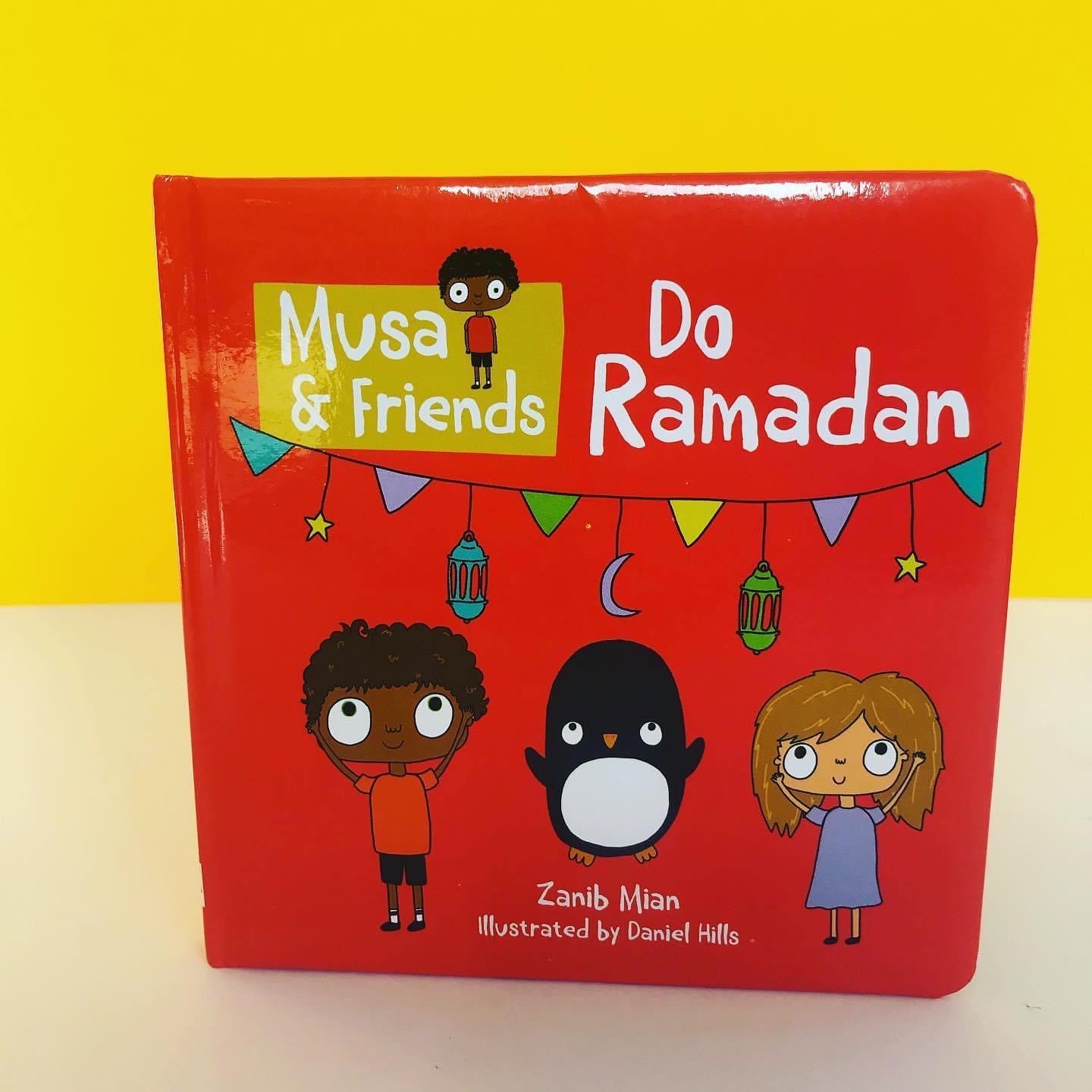 A children's book titled 'Musa and friends Do Ramadan' with a red background and illustrations of a boy and a penguin decorating a mosque.
