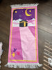 pink and purple prayer rug with Kaaba on a wooden floor