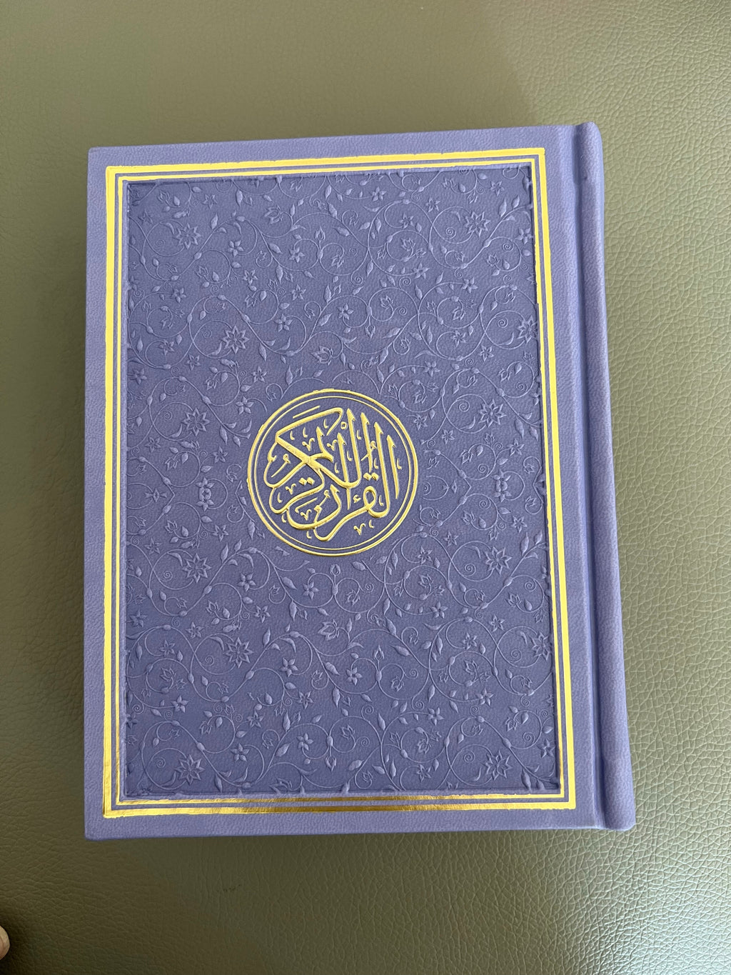 a photo of a purple quran with intricate design on a table