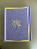 a photo of a purple quran with intricate design on a table