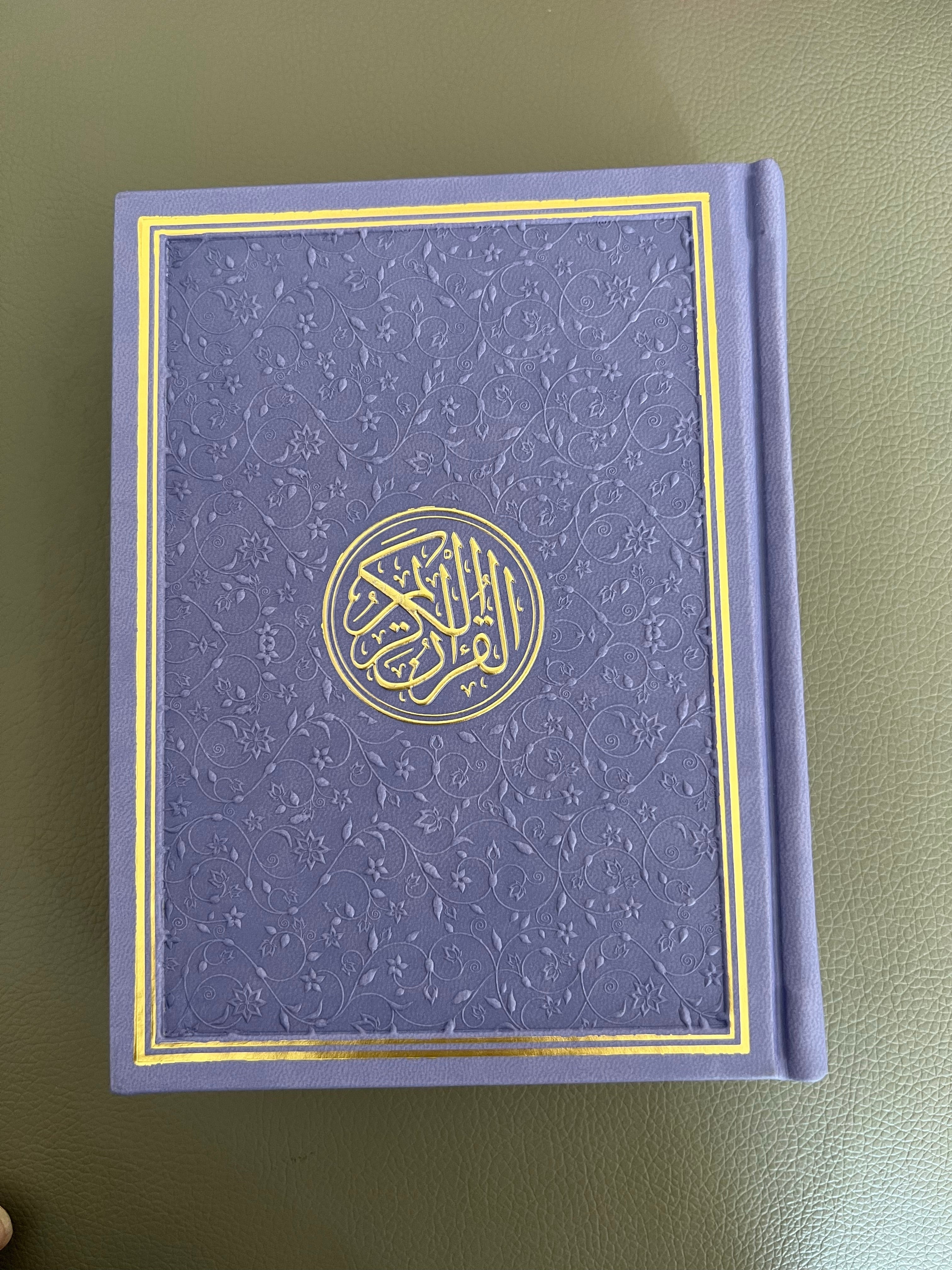 a photo of a purple quran with intricate design on a table